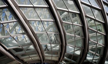 © Reuters. A cleaner walks inside a glass wall of a building under construction at a financial district in Beijing