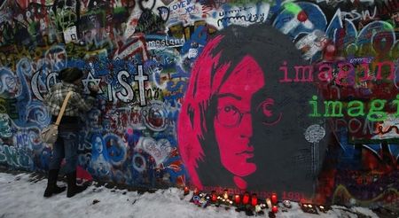 © Reuters. A girl writes a message on the legendary John Lennon's Wall in the historical center of Prague