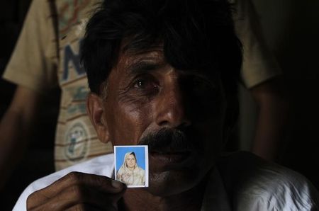 © Reuters. Muhammed Iqbal shows a picture of his late wife Farzana Iqbal at his residence in a village in Moza Sial