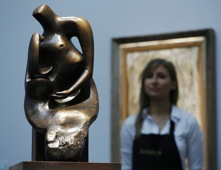 © Reuters. A Sotheby's employee poses with artist  Henry Moore's  "Working model for Mother and Child : Block Seat" at Sotheby's auction house in London