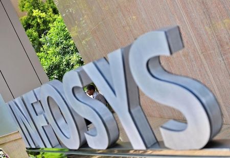 © Reuters. An employee is seen behind an Infosys logo at the company's campus in Bangalore