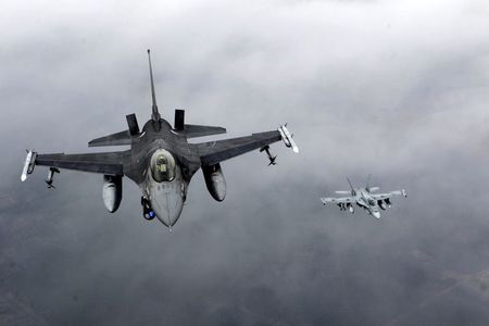 © Reuters. Portuguese Air Force fighter F-16 and Canadian Air Force fighter CF-18 Hornet patrol over Baltics air space, from the Zokniai air base near Siauliai
