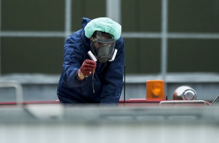 © Reuters. A man wearing a protective mask and suit inspects a container containing eggs and the bodies of culled chickens at a poultry farm, where a highly contagious strain of bird flu was found by Dutch authorities, in Hekendorp