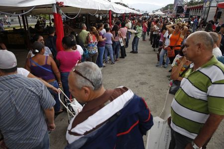 © Reuters. People stand in line to buy food at a state-run street market in Caracas