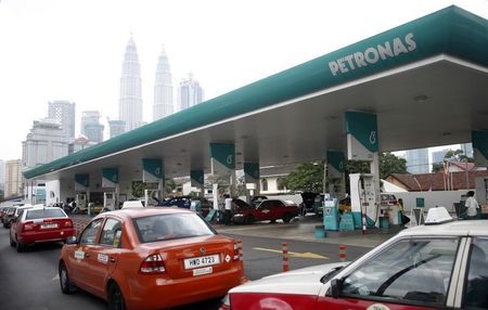 © Reuters. Motorists queue to fill up on natural gas at a Petronas station, with the company's headquarters at the landmark Petronas Twin Towers visible in the background, in Kuala Lumpur