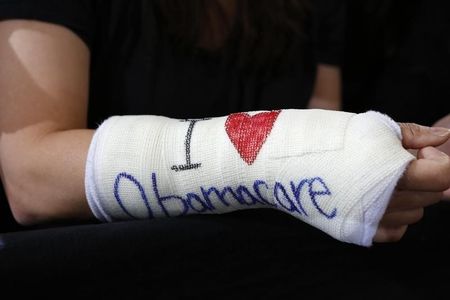 © Reuters. Park of Cambridge wears cast for her broken wrist with "I Love Obamacare" written upon it prior to U.S. President Barack Obama's arrival to speak about health insurance at Faneuil Hall in Boston
