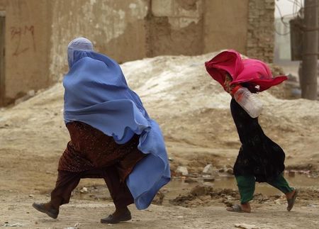 © Reuters. An Afghan woman walks with her daughter during a wind storm in Kabul