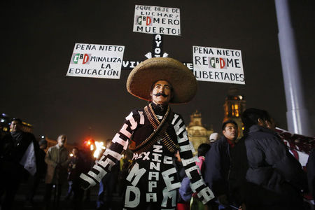© Reuters. A demonstrator dressed as a revolutionary carries signs on his hat during a protest in support of 43 missing Ayotzinapa students in Mexico City