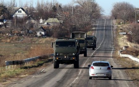 © Reuters. Military trucks are seen through a car window as they drive along a road on the territory controlled by the self-proclaimed Donetsk People's Republic in Bezimenne, eastern Ukraine