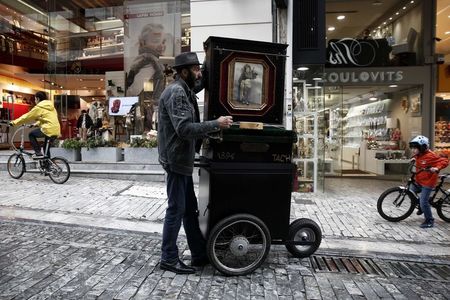 © Reuters. A man plays a laterna at a central market street of  Athens