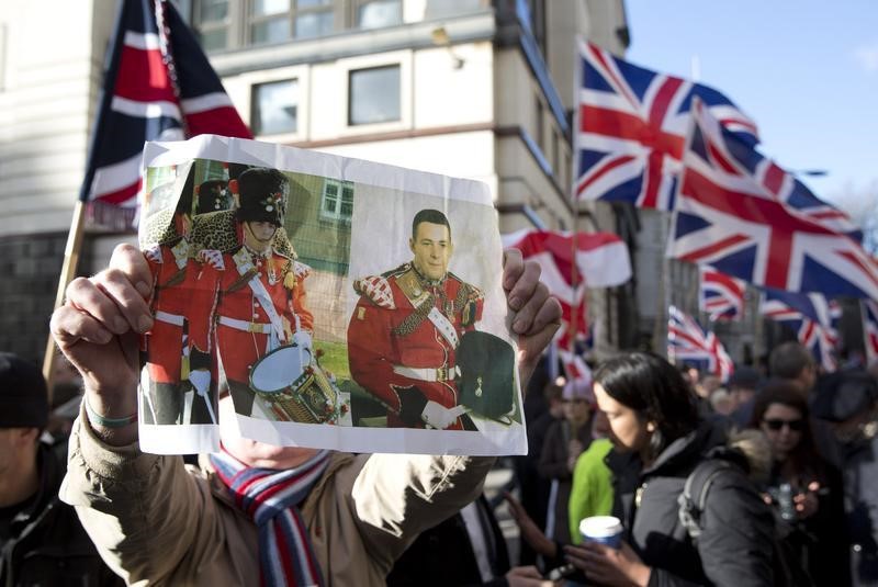 © Reuters. A demonstrator holds a picture of murdered soldier Lee Rigby during a protest outside the Old Bailey courthouse in London