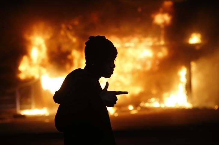 © Reuters. Homem passa por prédio em chamas em Ferguson, no Estado norte-americano do Missouri