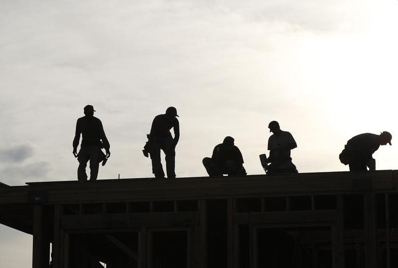 © Reuters. Workers are silhouetted as they stand on the roof of a building under construction in Los Angeles