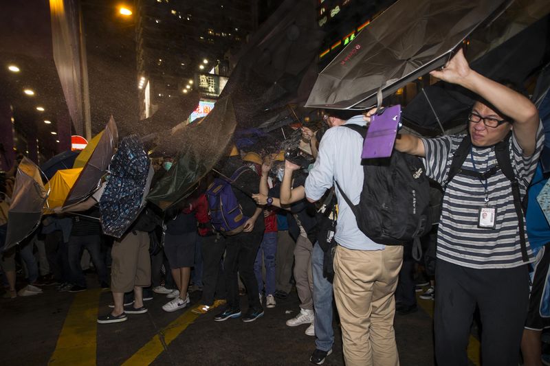 © Reuters. Protesters are sprayed with "tear spray" by riot police during a confrontation at Mongkok shopping district in Hong Kong