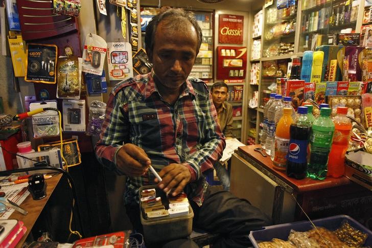 © Reuters. A shopkeeper takes out a cigarette from a box for a customer in Kolkata