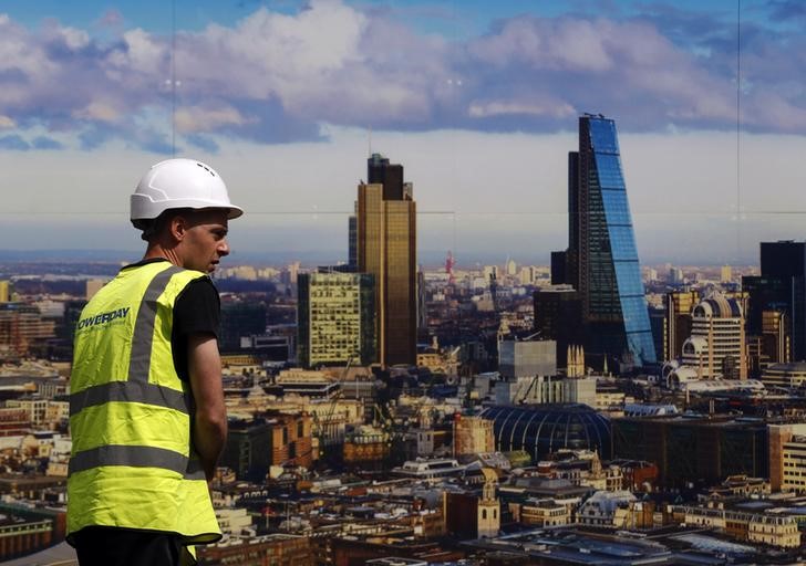 © Reuters. A worker walks past a picture of the London skyline outside the sales office of a property development in central London