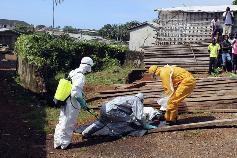 © Reuters. Health workers remove the body a woman who died of Ebola virus in the Aberdeen district of Freetown