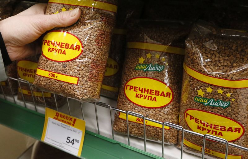 © Reuters. A woman picks a pack of buckwheat groats at a food market in Krasnoyarsk