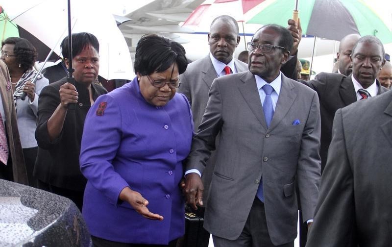 © Reuters. Zimbabwean President Robert Mugabe is greeted by Vice President Joice Mujuru as he returns home to Harare
