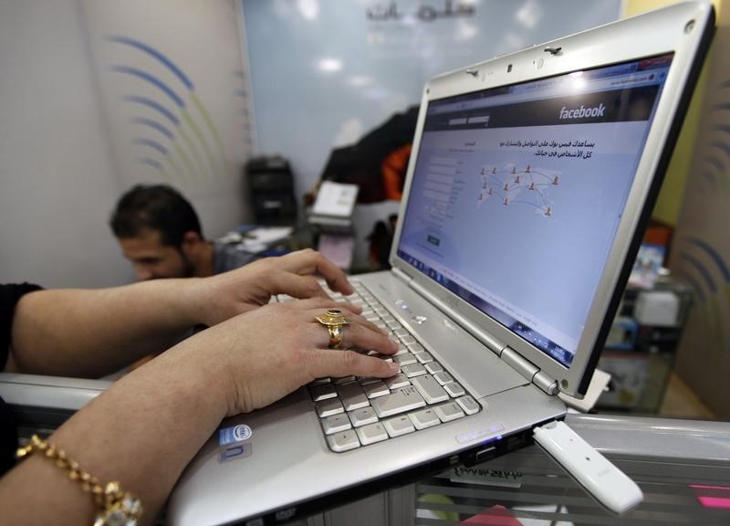 © Reuters. A woman uses wireless Internet at an internet shop in Baghdad