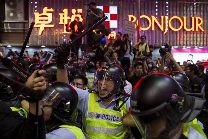 © Reuters. A riot police officer holds a baton as he confronts pro-democracy protesters in Mongkok