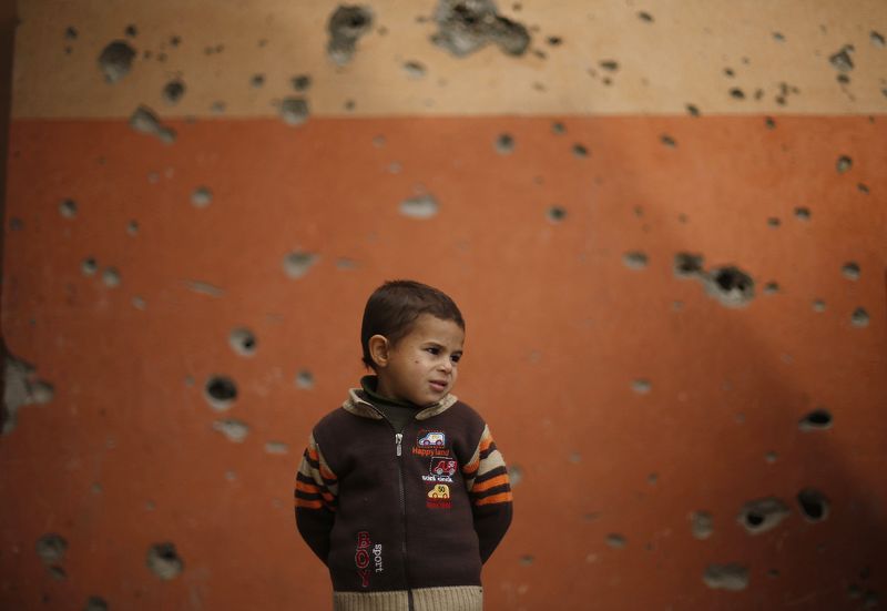 © Reuters. A Palestinian boy stands outside a mosque on a winter day in Beit Hanoun town
