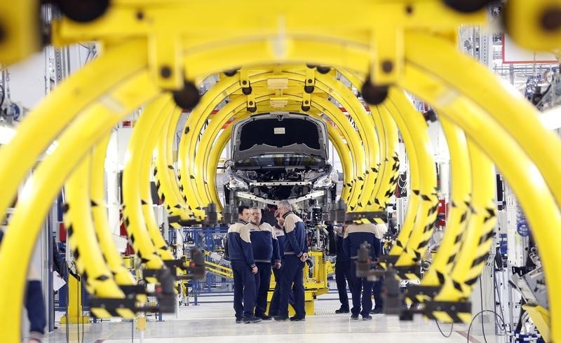 © Reuters. Employees stand in front of a new car at the Maserati new opening plant in Turin