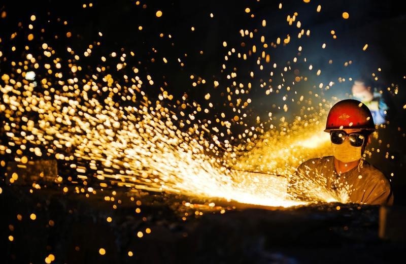 © Reuters. A worker wearing protective glasses welds steel products at a heavy equipment manufacturing factory in Luoyang