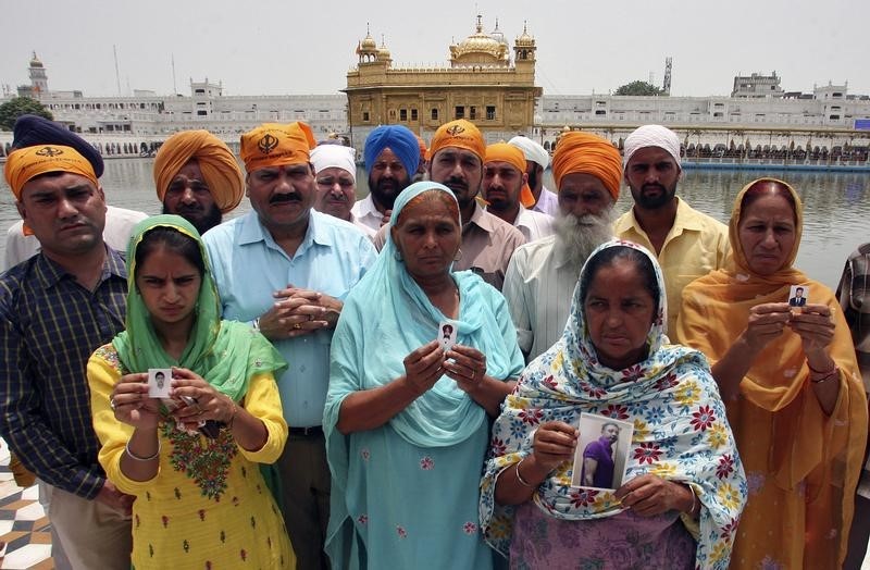© Reuters. Relatives pose with the photographs of Indian workers, who have been kidnapped in Iraq, in front of the holy Sikh shrine, the Golden Temple, in Amritsar