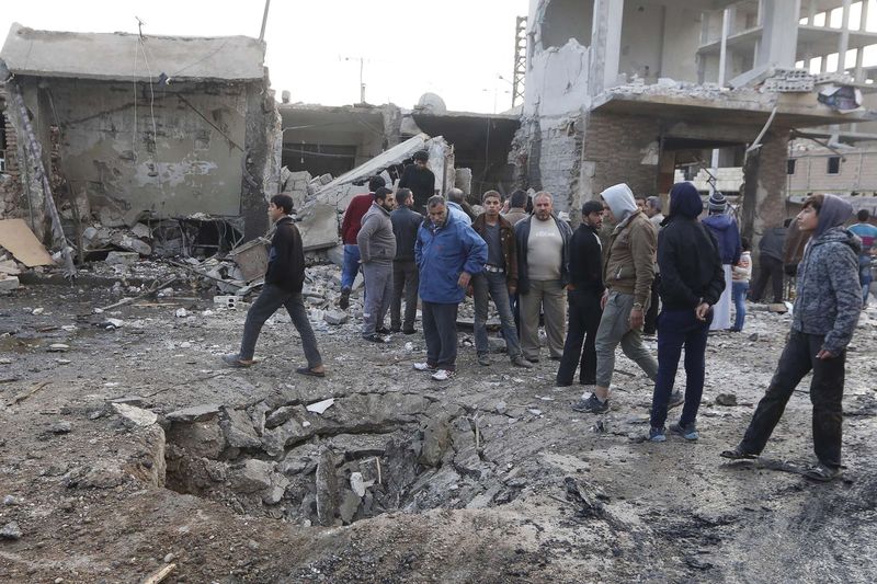 © Reuters. People inspect a site after hit by what activists said were air strikes by forces loyal to Syria's President Bashar al-Assad in Raqqa, eastern Syria, which is controlled by the Islamic State