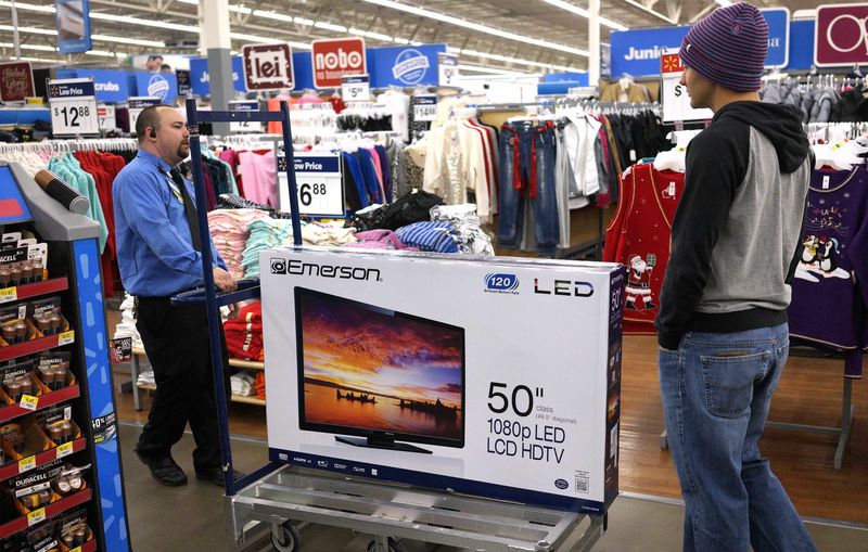 © Reuters. A Walmart employee helps a customer with a 50" TV on sale for $218 on Black Friday in Broomfield