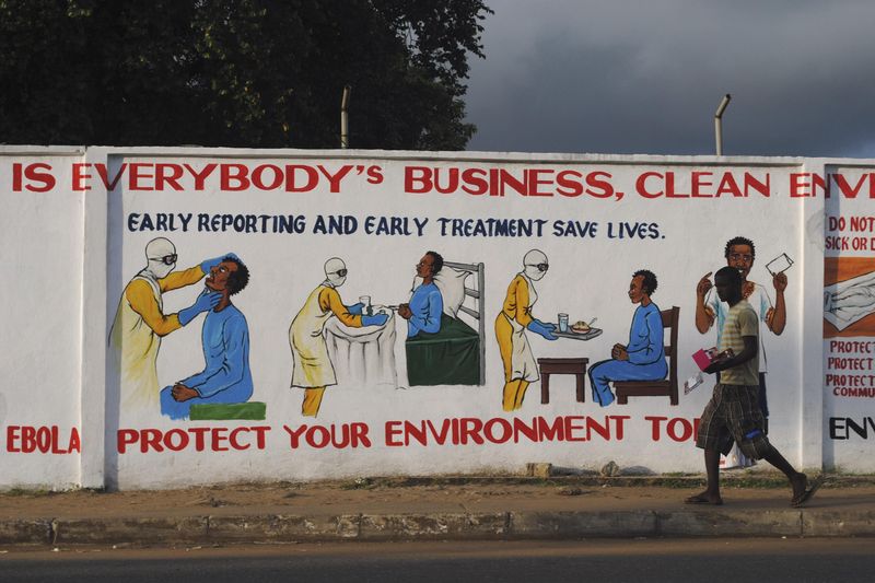 © Reuters. A man walks by a mural with health instructions on treating the Ebola virus, in Monrovia