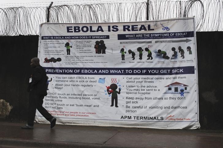 © Reuters. A man walks by a sign that reads "Ebola is real" in Monrovia