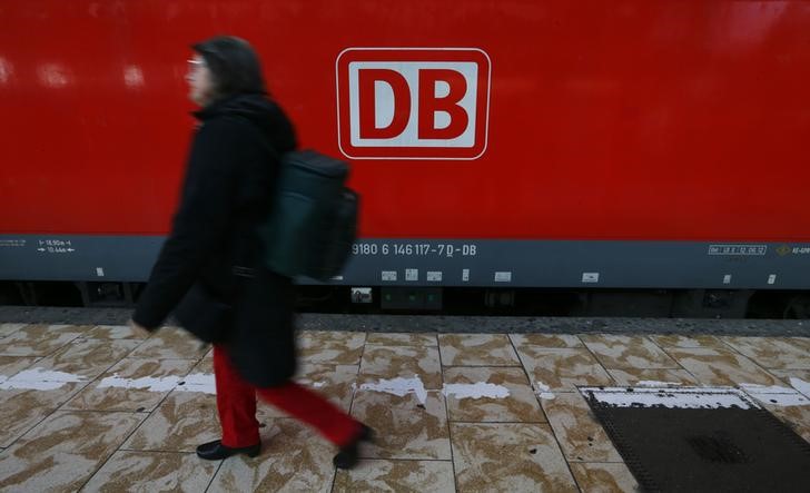© Reuters. A woman walks past a train of Deutsche Bahn railway operator at the main train station in Frankfurt