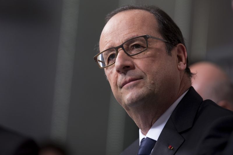 © Reuters. French President Francois Hollande listens to  ArcelorMittal workers as he visits their union meeting room during a visit at the ArcelorMittal Steel Factory in Florange