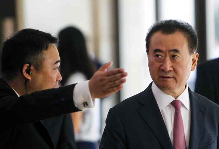 © Reuters. A man shows the way for Wang Jianlin in Shenzhen