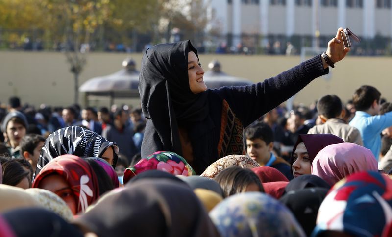 © Reuters. A student of Tevfik Ileri Imam Hatip School takes a "selfie" as she joins others in waiting for the arrival of President Tayyip Erdogan for the opening ceremony in Ankara