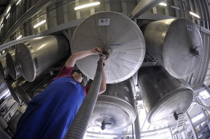 © Reuters. A worker fixes a hose on a tank for liquid paint in the factory Helios in Kolicevo