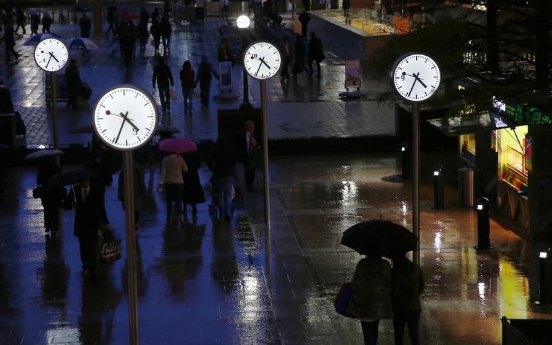 © Reuters. Workers walk in the rain at the Canary Wharf business district in London