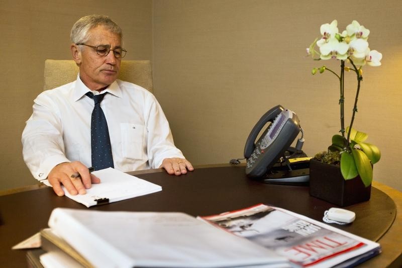 © Reuters. U.S. Secretary of Defense Hagel listens on speaker phone during a conversation with Carter and other senior Defense Department officials about the U.S. government shutdown, at his hotel in Seoul