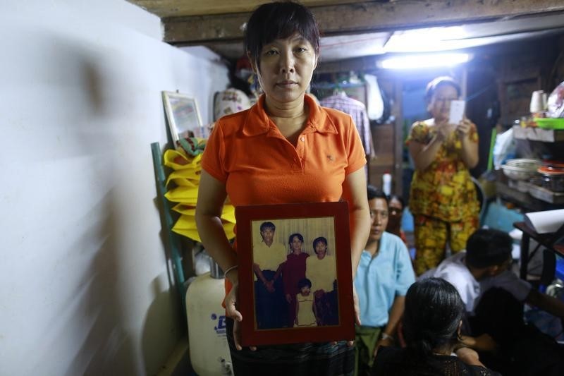 © Reuters. Than Dar, the wife of slain journalist Par Gyi, holds a family photograph showing herself, her husband and daughter posing with Aung San Suu Kyi at their home, in Yangon