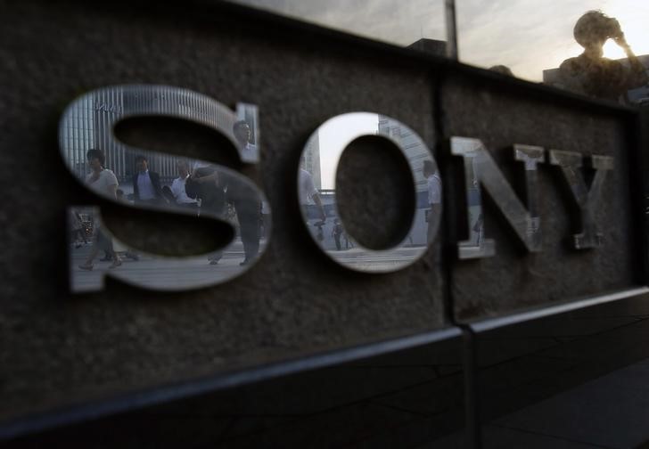 © Reuters. Pedestrians are reflected in a logo of Sony Corp outside its showroom in Tokyo