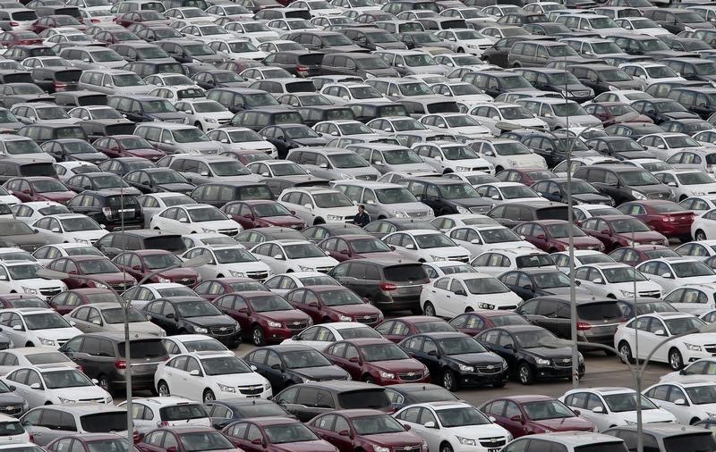 © Reuters. An employee yawns as he walks among General Motors' new Chinese-made cars at a parking lot in Shenyang, Liaoning province