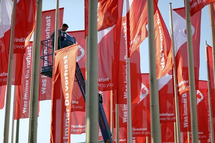 © Reuters. A worker installs advertising flags of British telecommunications company Vodafone outside the IFA Electronics show in Berlin 
