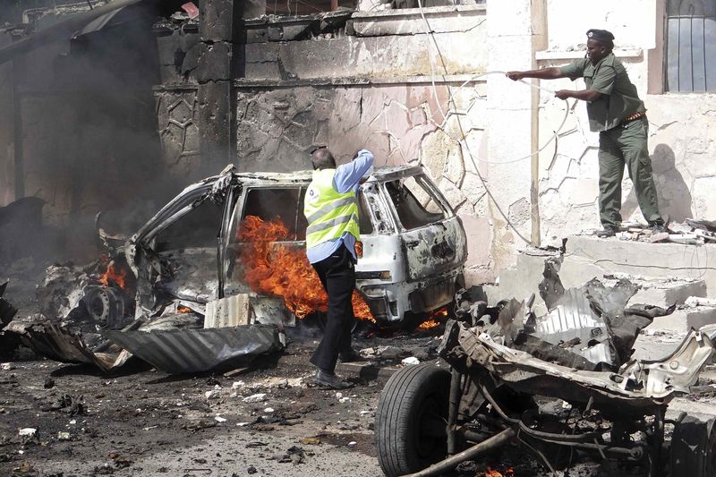 © Reuters. Forças de segurança da Somália tentam apagar fogo em local de ataque de carro-bomba a um comboio da ONU na capital, Mogadíscio