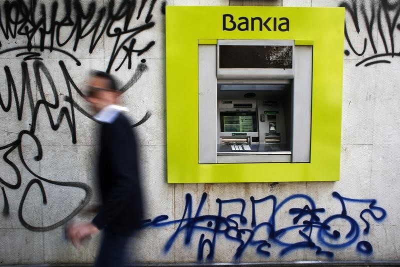 © Reuters. Man walks past a Bankia bank branch with graffitti on it in Madrid