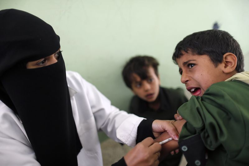 © Reuters. File photo of a boy reacting while receiving a vaccination against measles and rubella in a school in Sanaa
