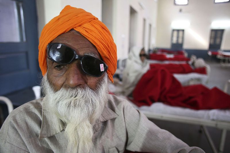 © Reuters. A man sits on a bed while waiting for treatment at a hospital after undergoing cataract removals from a free eye surgery camp in Amritsar