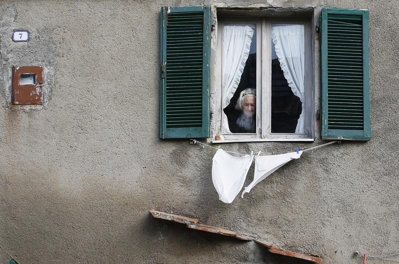 © Reuters. Una donna anziana alla finestra in un paesino toscano 