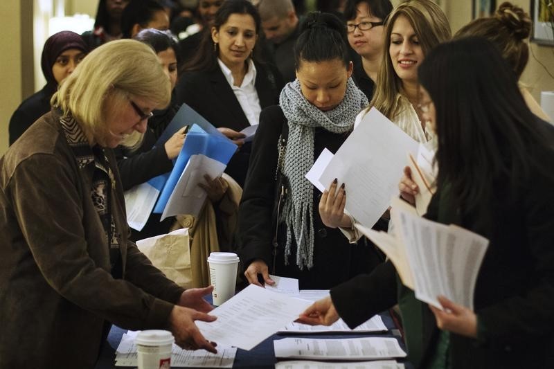 © Reuters. Job seekers adjust their paperwork as they wait in line to attend a job fair in New York